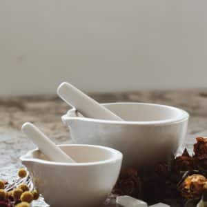 White Ceramic Mortar and Pestle surrounded by flowers and crystals